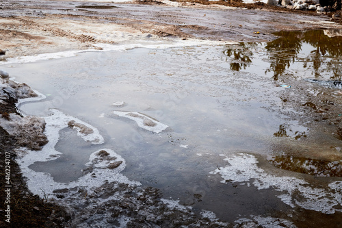 Ice and snow in puddles in spring or autumn time. Thaw after winter in nature landscape