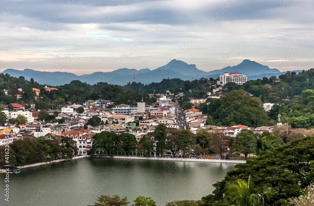 Mountain view of the city pond and buildings of Kandy city against the overcast sky in Sri Lanka