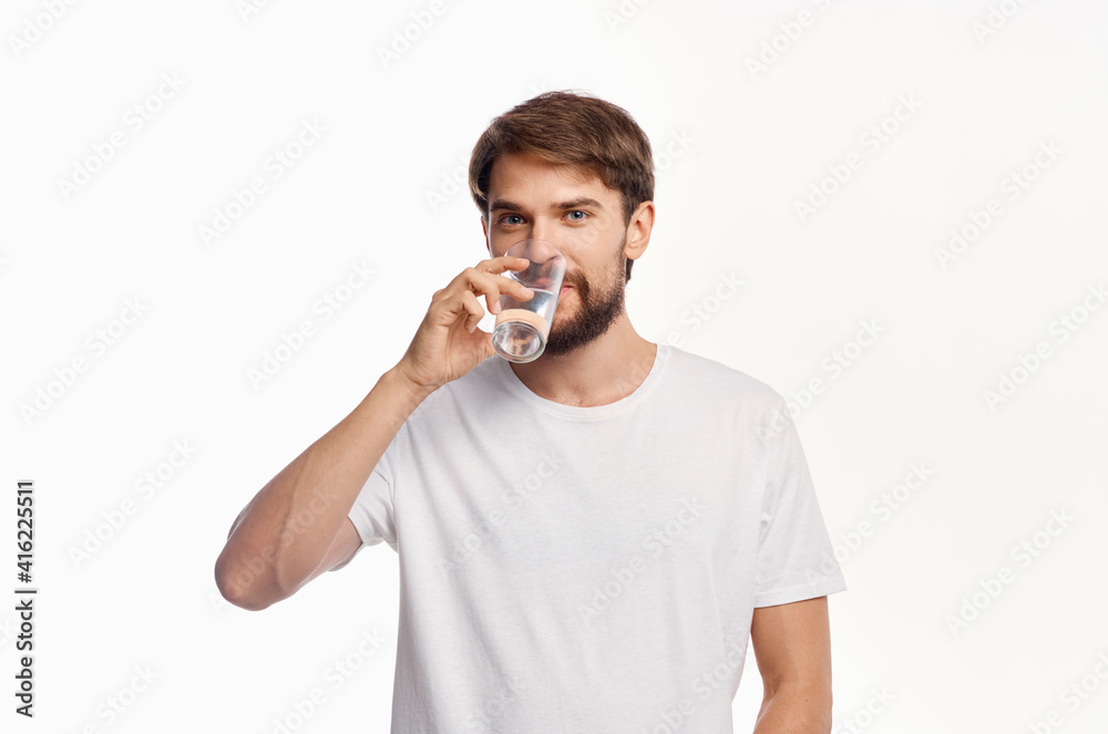 joyful man with a glass of water white t-shirt light background joyful man with a glass of water white t-shirt light background