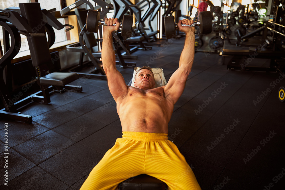 Naklejka premium Sports enthusiast lifting dumbbells at the gym