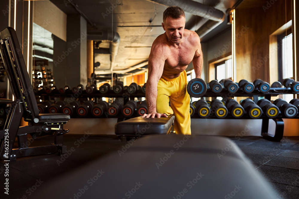 Obraz premium Serious sporty man doing his workout programme at the gym