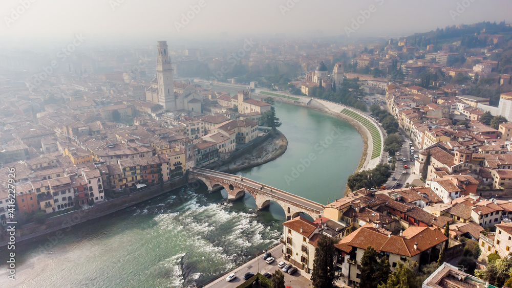 Aerial view of Verona crossed by the Adige river and shrouded in winter fog.