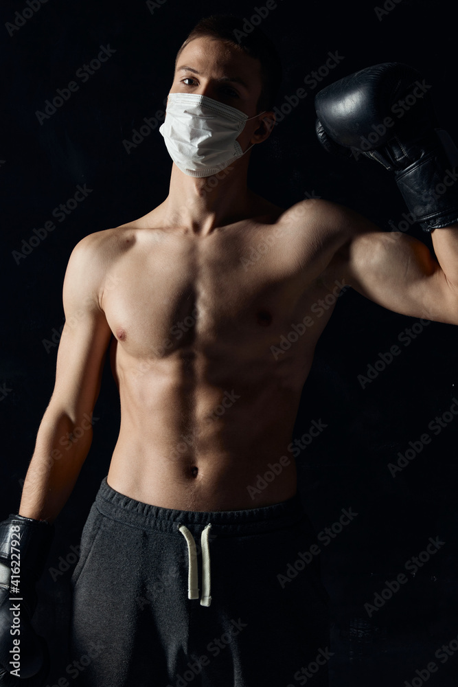 boxer in a medical mask on a black background gloves athlete naked torso 
