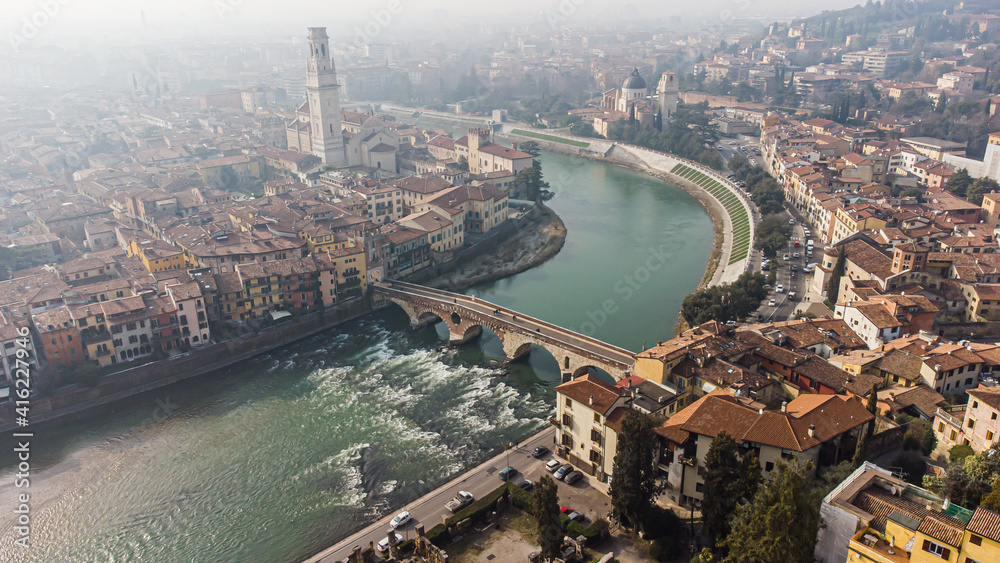 Aerial view of Verona crossed by the Adige river and shrouded in winter fog.