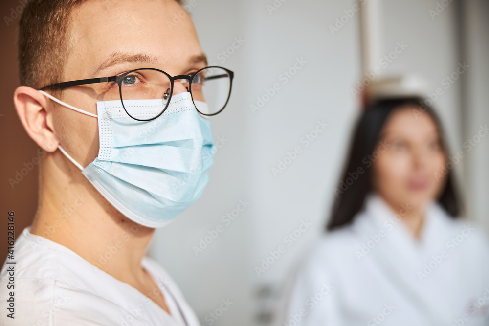 Thoughtful bespectacled physician receiving a patient at his office Thoughtful bespectacled physician receiving a patient at his office