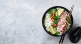 Pho Bo vietnamese soup with beef and rice noodles on concrete background, top view, copy space