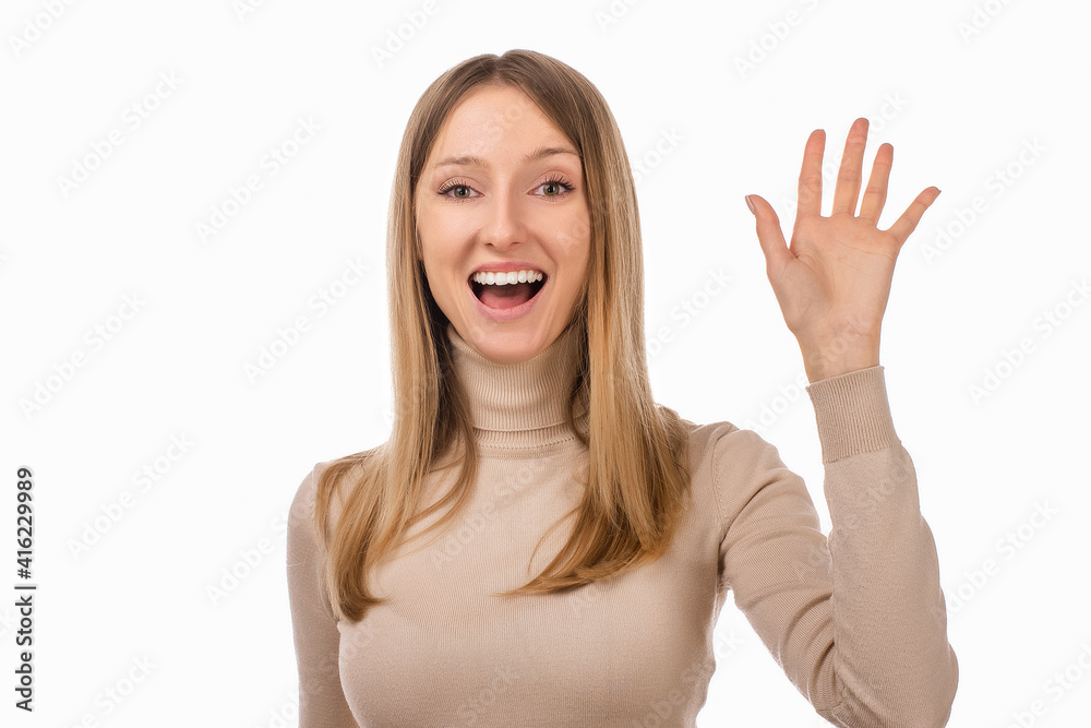 Friendly blond girl is saying hello, smiling joyfully and friendly, waving her hand, showing five fingers Friendly blond girl is saying hello, smiling joyfully and friendly, waving her hand, showing five fingers