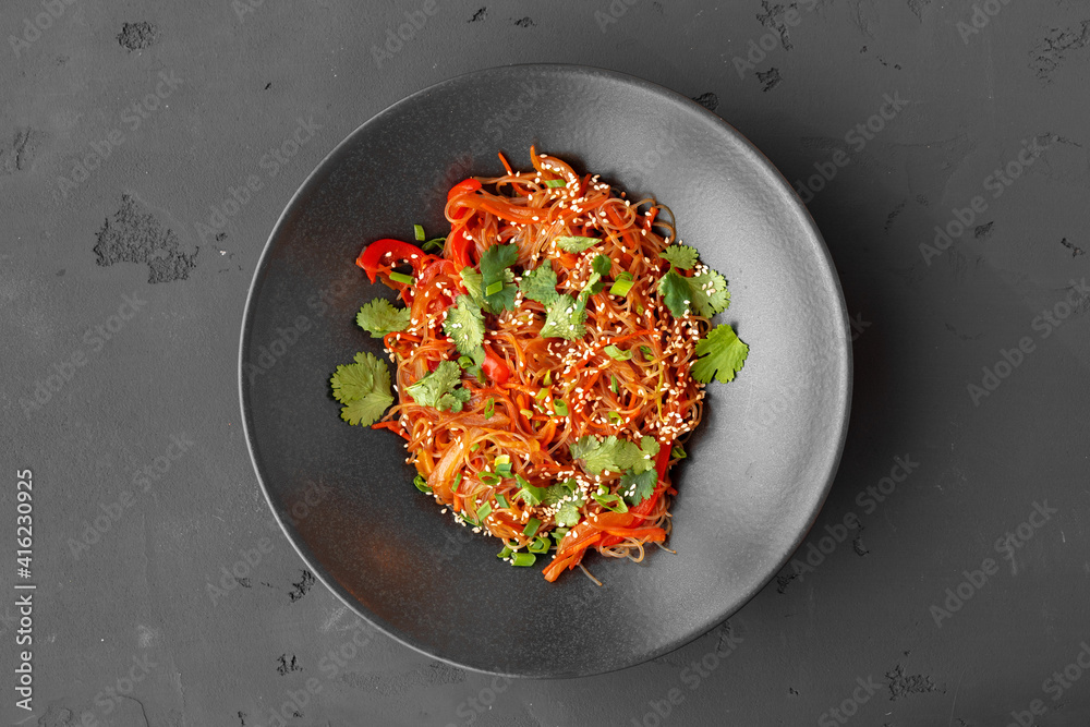 Top view of wok noodles with vegetables and meat in bowl on gray background Top view of wok noodles with vegetables and meat in bowl on gray background