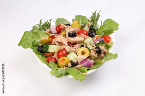 Tuna fish meat salad cucumber tomato onion black green olive leaf lettuce on white plate over white background