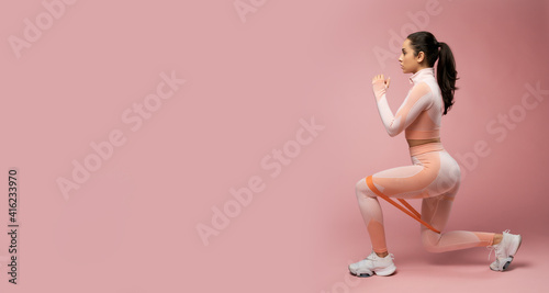 Fotografiet Website header of Sporty young woman doing exercise with resistance band