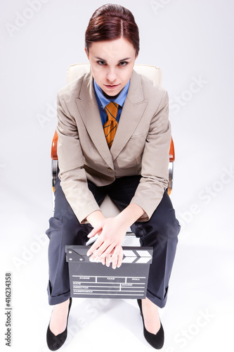 Portrait of Seriously Looking Caucasian Female Posing in Beige Blazer in Chair with Actioncut Indoors. photo