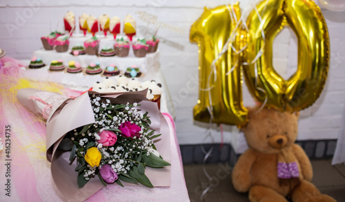 bouquet and sweets on the table for the birthday of a ten year old girl © Liubov Kartashova