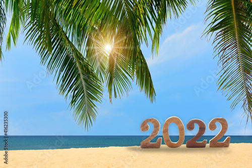 Fototapeta Naklejka Na Ścianę i Meble -  New year 2022 with coconut palm leaves on tropical beach with cloudy sky background, happy travel holiday concept and natural relaxation idea