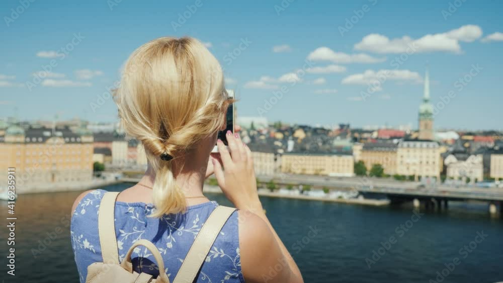 A woman is photographing a beautiful view of the city of Stockholm in Sweden, rear view. Tourism in Scandinavia concept A woman is photographing a beautiful view of the city of Stockholm in Sweden, rear view. Tourism in Scandinavia concept