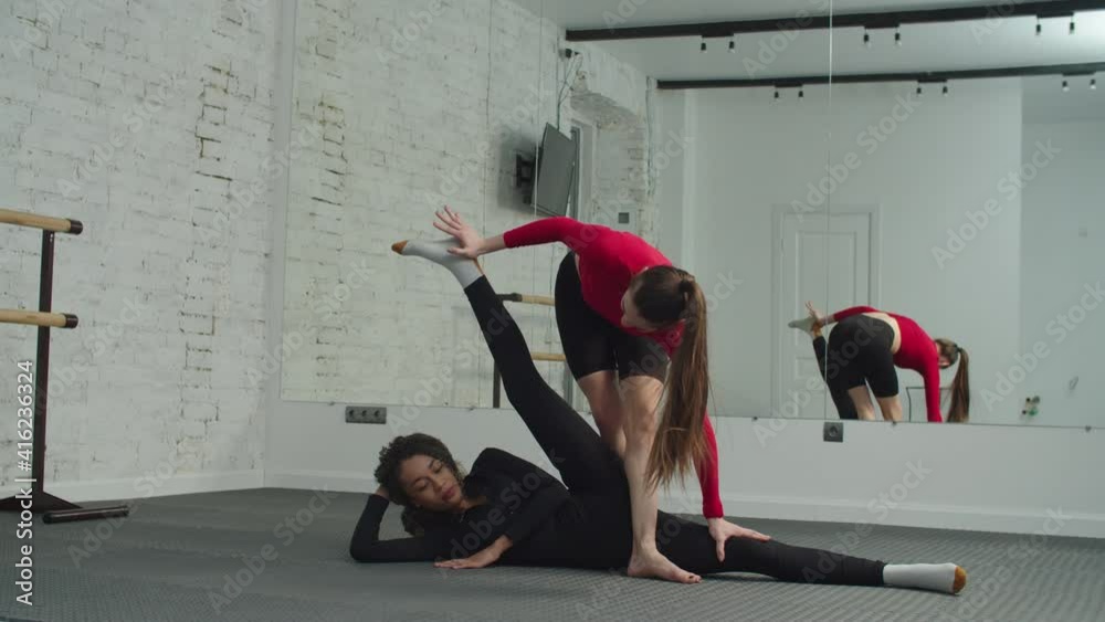 Straddle Split Skillful pretty personal female trainer helping charming sporty fit ...