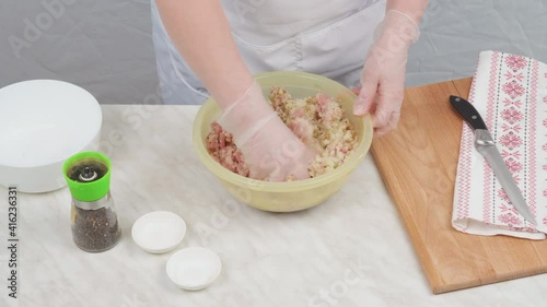 Knead minced pork with onions with gloved hands.