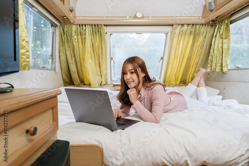 Billede på lærred woman using laptop computer on bed of a camper RV van motorhome