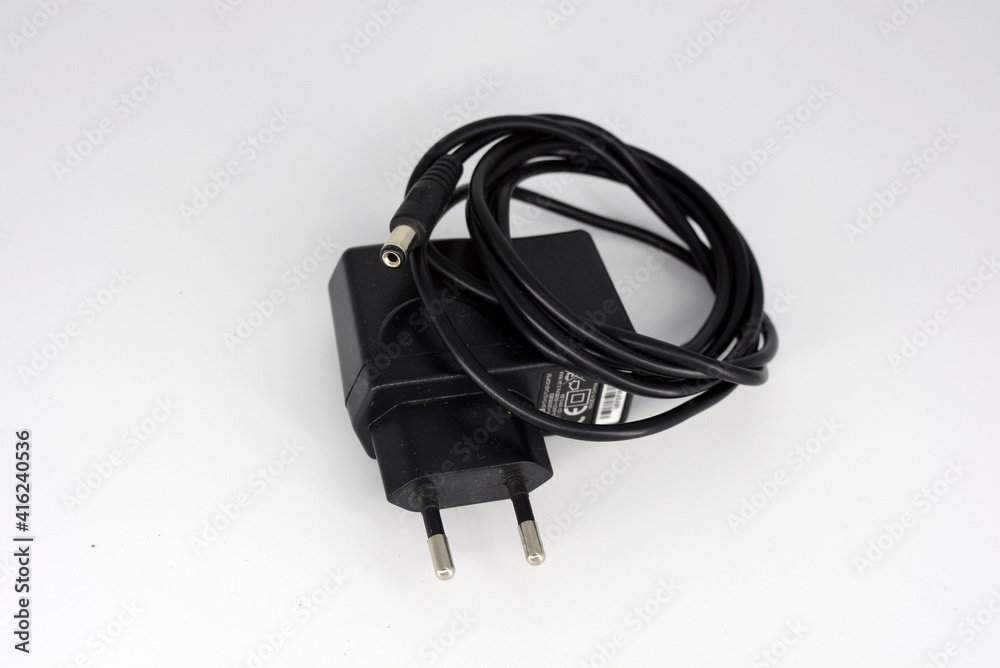Black metal plug, power supply for connecting and charging the phone into a reinstate 220 in a white plastic background.