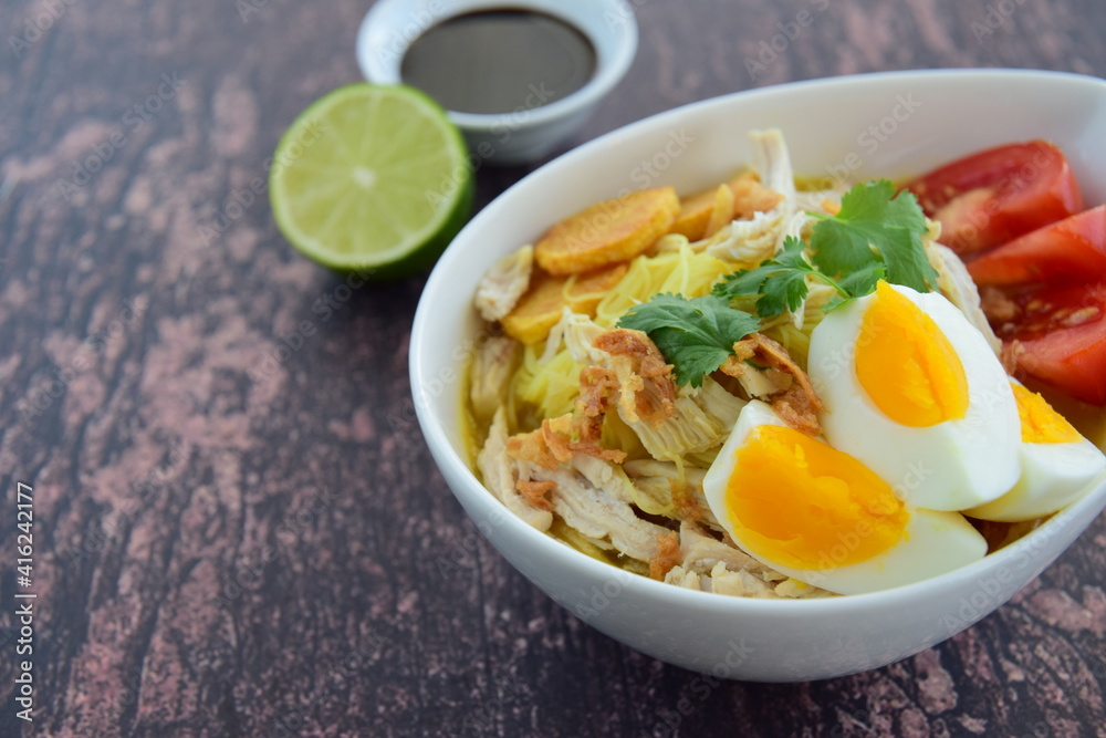 Soto Ayam, Indonesian food, yellow spicy chicken soup with vermicelli, fried potato, hard boiled egg and fried shallot.
