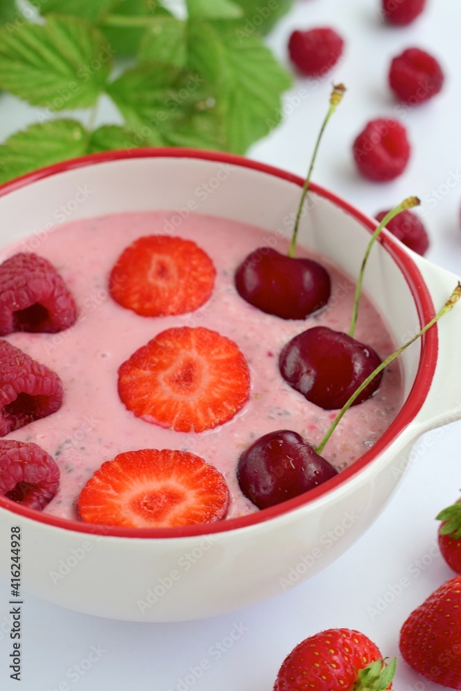 Breakfast berry smoothie bowl topped with raspberry, strawberry and cherry on white background Breakfast berry smoothie bowl topped with raspberry, strawberry and cherry on white background