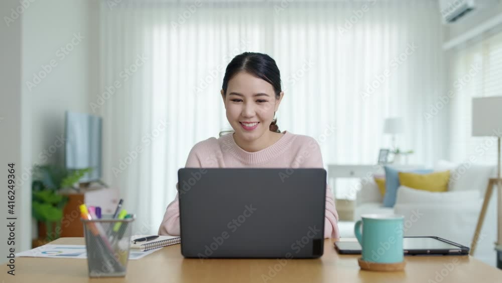 Zoom out young asia attractive beautiful female student sit at home apartment on wooden desk in room open laptop computer ready to start work remotely from home or learning online feel happy positive. Zoom out young asia attractive beautiful female student sit at home apartment on wooden desk in room open laptop computer ready to start work remotely from home or learning online feel happy positive.