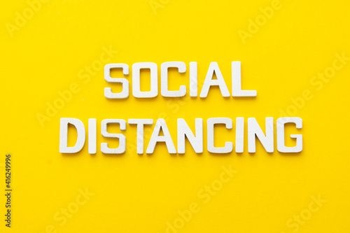 Social distancing word wooden letters yellow background. © Inga