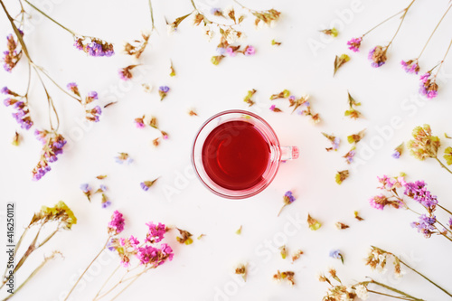 Glass cup of herbal tea on white backgrund with dry petal. photo