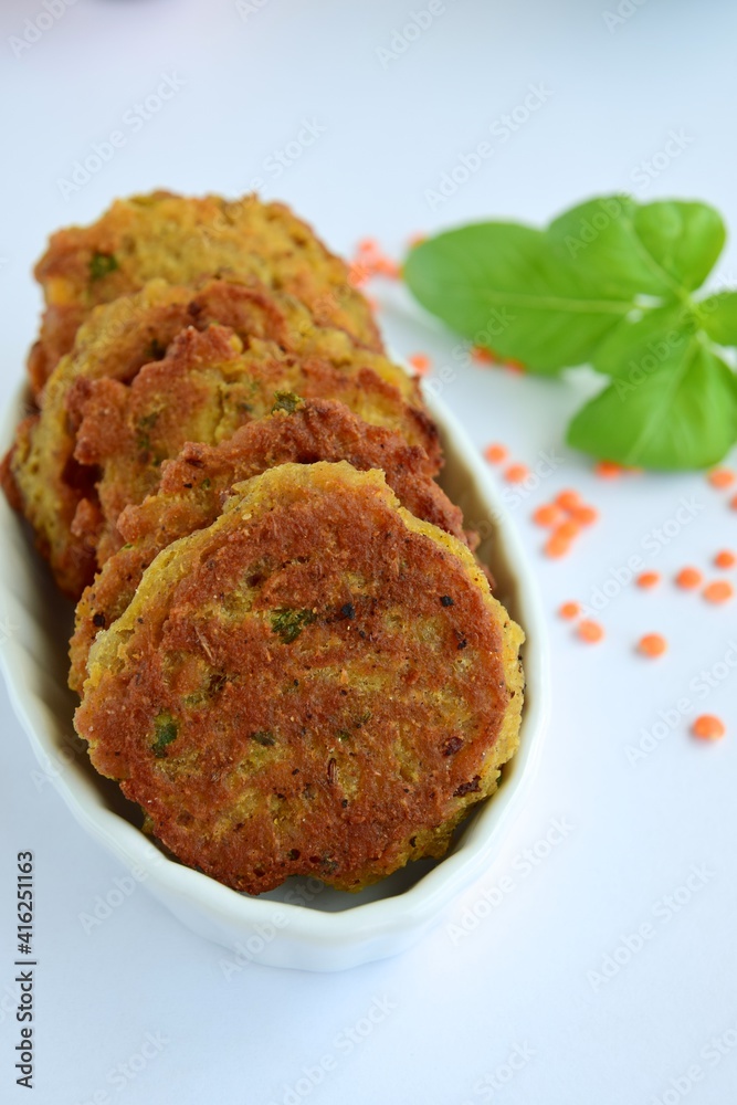 Patties of red lentils with basil leaf on white background Patties of red lentils with basil leaf on white background