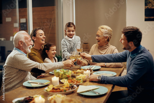 cheerful extended family toasting during dinner at dining table.