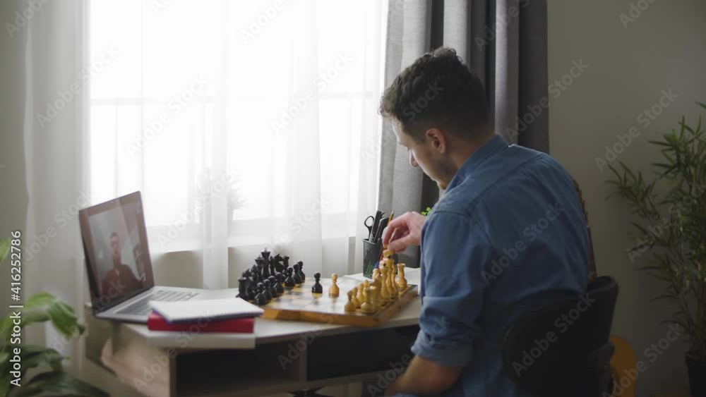 A young cute man plays chess with a different video of a house during a pandemic A young cute man plays chess with a different video of a house during a pandemic