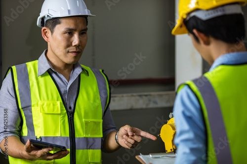 Senior and junior engineers talking together with intimated manner beside the machine in factory. Concept for good teamwork and unity of colleauges