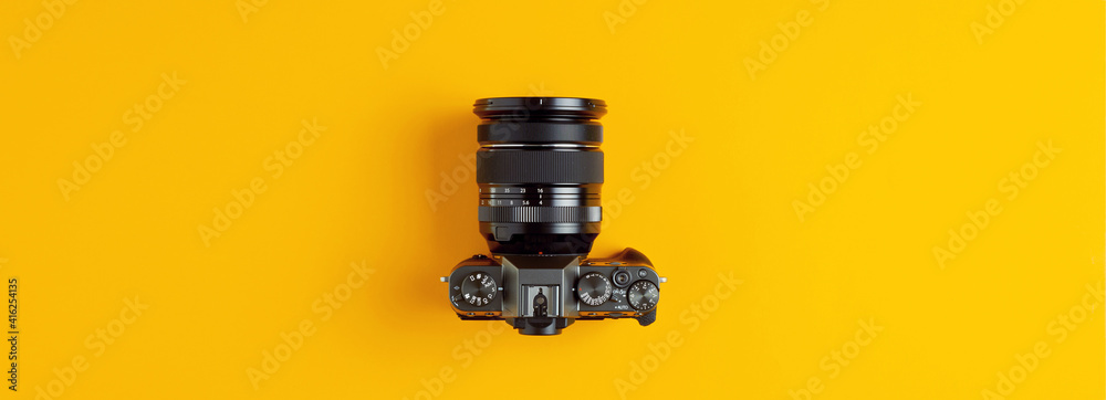 Black retro camera on yellow background. Photography concept with flat lay view.