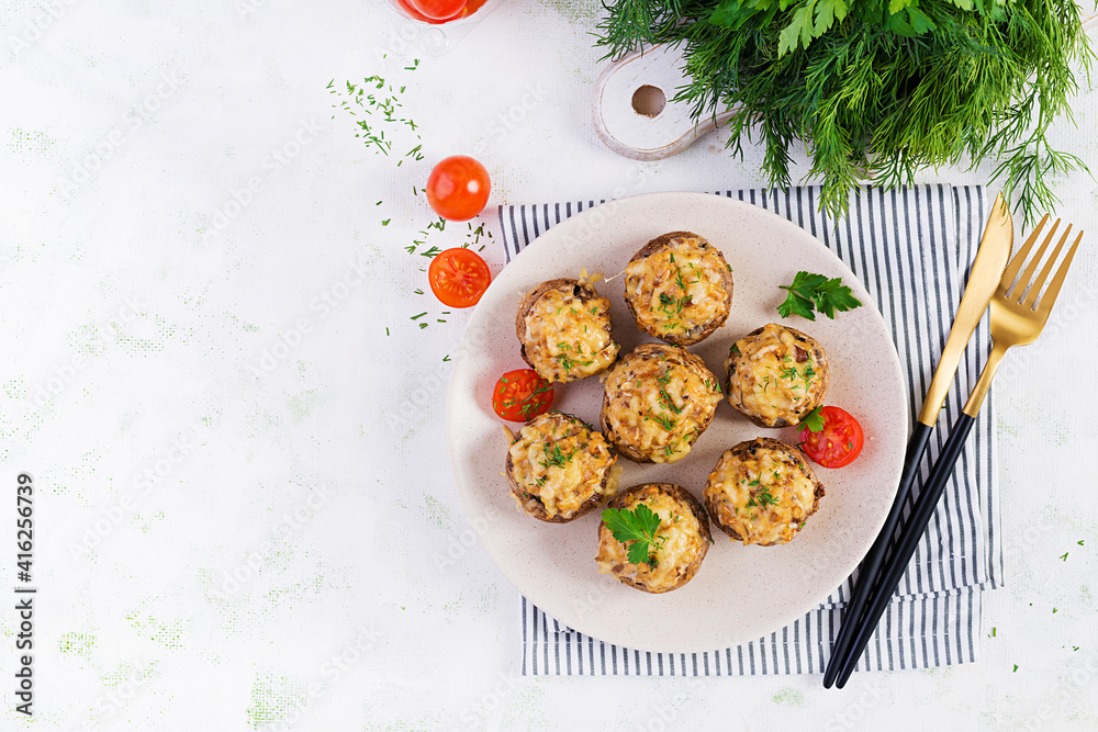 Baked mushrooms stuffed with chicken minced meat, cheese and herbs on light plate. Top view, above, copy space