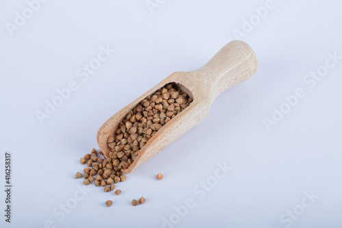 Bunch of uncooked buckwheat on wooden spoon