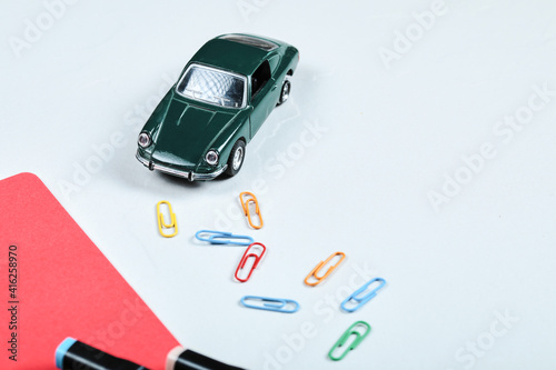 Colorful pencils, clips, red paper and toy car on white background