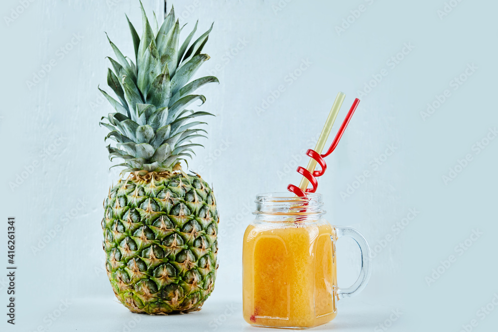 Ripe pineapple and a glass of juice on blue background Ripe pineapple and a glass of juice on blue background