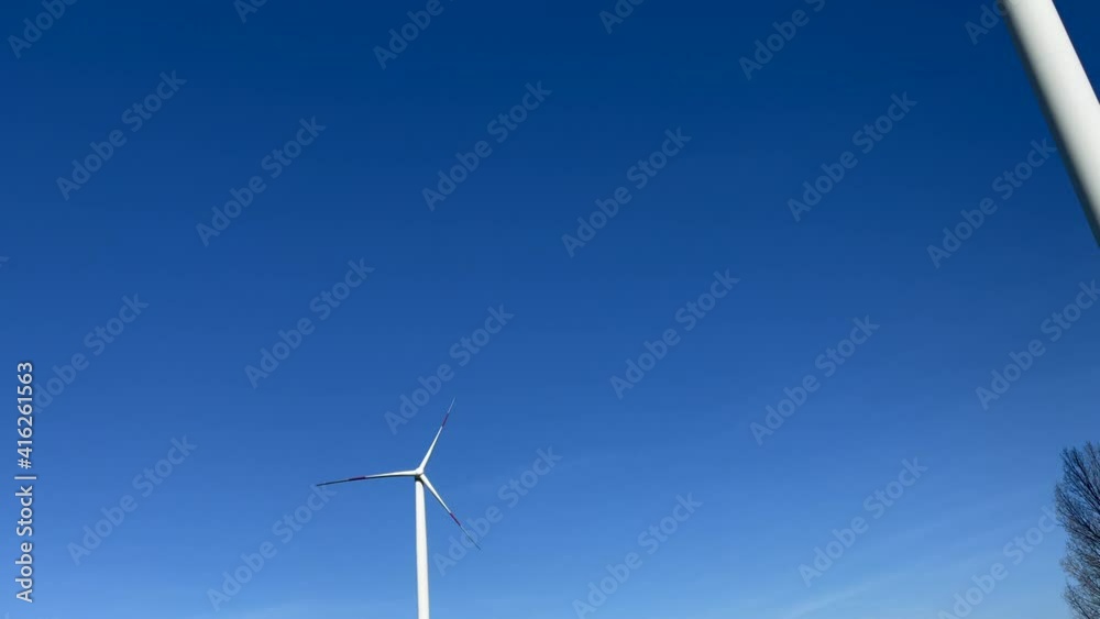 Tilt down shot of windmill turbines working on rural countryside during sunny day and clear blue sky. Tilt down shot of windmill turbines working on rural countryside during sunny day and clear blue sky.
