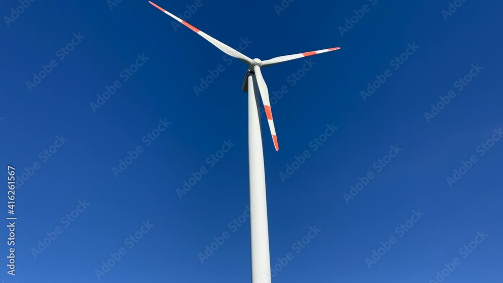 Slow motion shot of wind turbine producing renewable energy during sunny day and blue sky in background. Slow motion shot of wind turbine producing renewable energy during sunny day and blue sky in background.