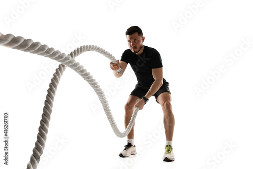 Ropes. Caucasian professional sportsman training isolated on white studio background. Muscular, sportive man practicing. Copyspace. Concept of action, motion, youth, healthy lifestyle.