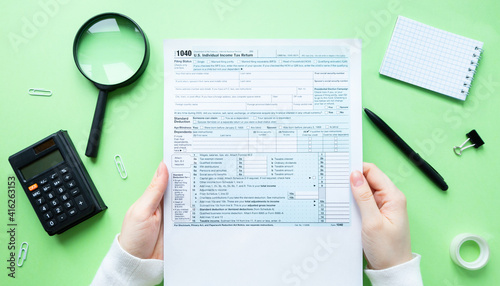 A man is holding a 1040 Individual Income Tax Return