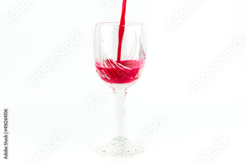 Crystal wine glass with red liquid on a white background