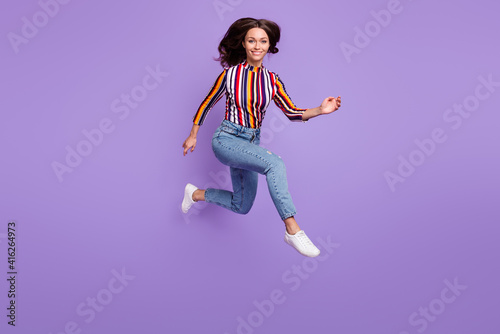 Full length body size photo of pretty girl jumping up running smiling isolated on vibrant purple color background