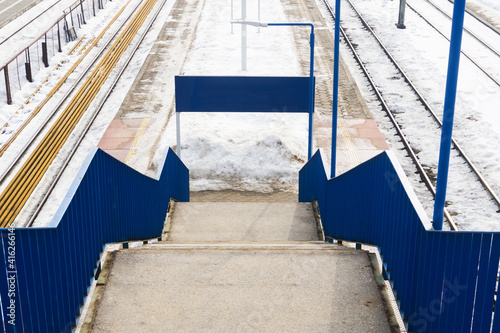 Train station stairs. Railway top view background. Footbridge over train track. White transportation background. Winter landscape. Snow on the railway. Icy train plaftorm. Train station covered in s photo