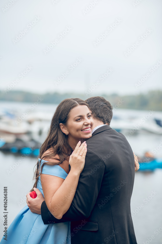 Happy young adult couple hugging outdoors