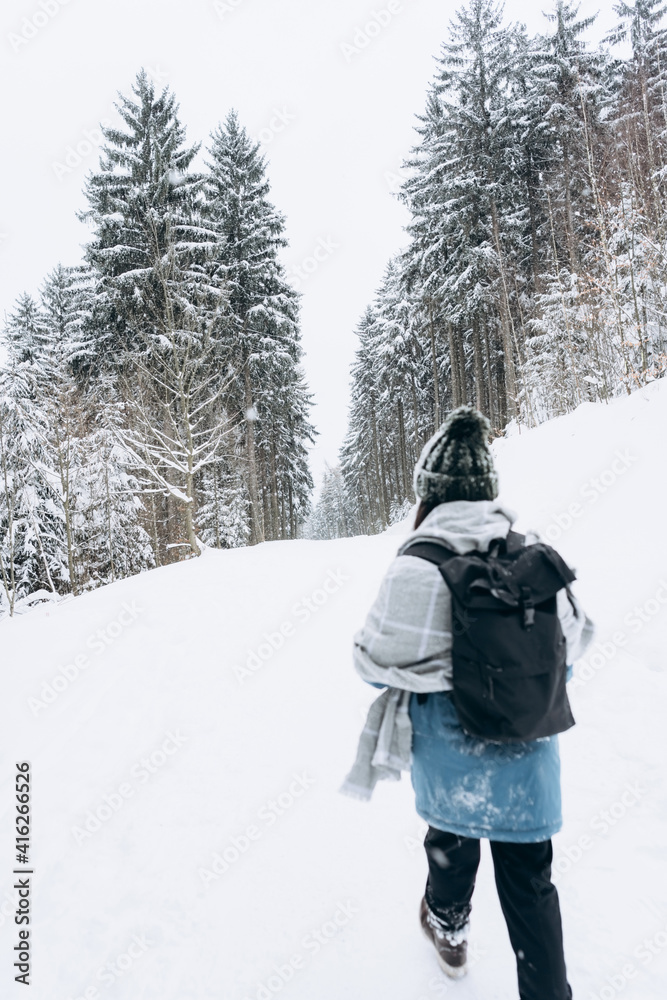 An active young tourist in warm winter clothes and with a backpack on the background of a beautiful snow-covered landscape.Hiking.Individual adventures.Local travel
