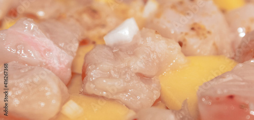 Raw chicken fillet slices with potatoes and onions. Cooking.