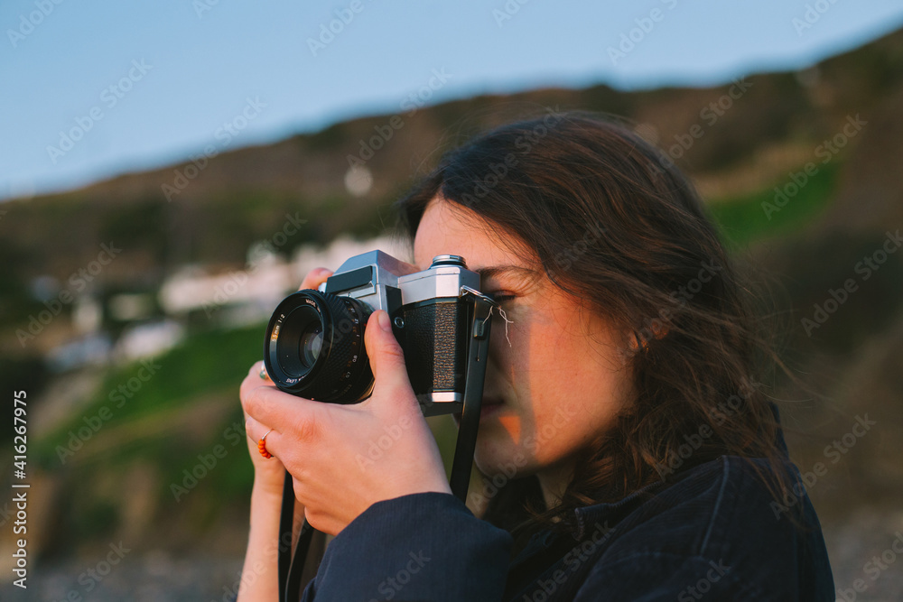 Portrait of young millennial woman practice making photos on analog film camera. Analog photography with vintage old equipment. Social media content creator or travel blogger Portrait of young millennial woman practice making photos on analog film camera. Analog photography with vintage old equipment. Social media content creator or travel blogger