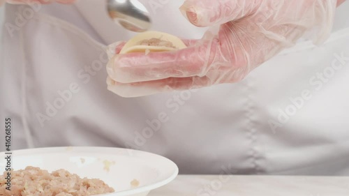 Making homemade dumplings. Close-up of female hands in gloves sculpt dumplings.