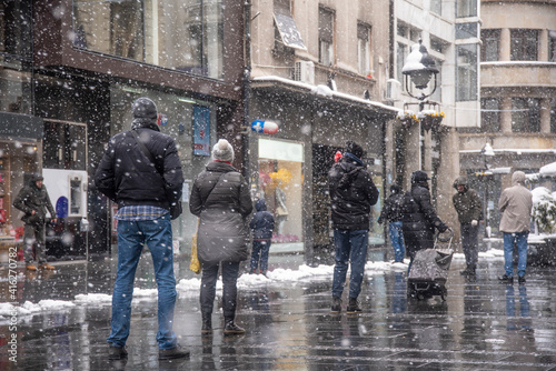 People stand in long queues on snowy day as they wait to enter a pharmacy store, drugstore to buy things for health during coronavirus epidemic situation - Covid-19. Belgrade, Serbia - 24.03.2020