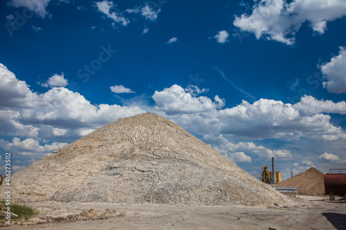 Asphalt mixing plant  on background . Heap of sand on foreground. Blue sky with beauty clouds. Panoramic view.